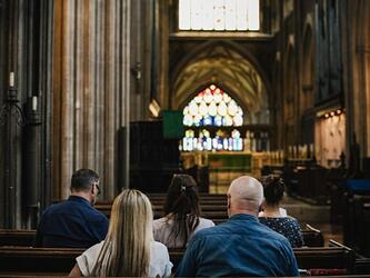 members of congregation shown from behind, sitting on pews in church